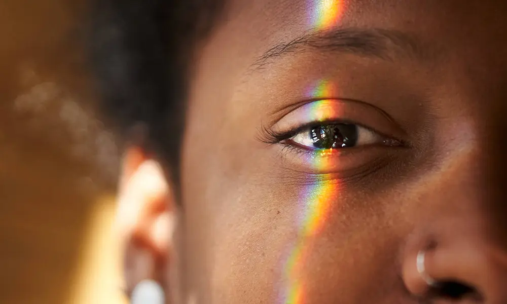 一个黑人眼睛的特写，多色的光线照在上面，说明视网膜神经节细胞是如何运作的.